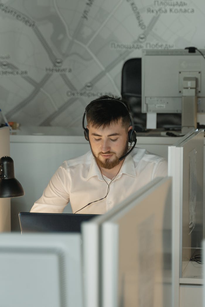 services-img Caucasian man wearing black headphones working on a laptop in a call center office cubicle.